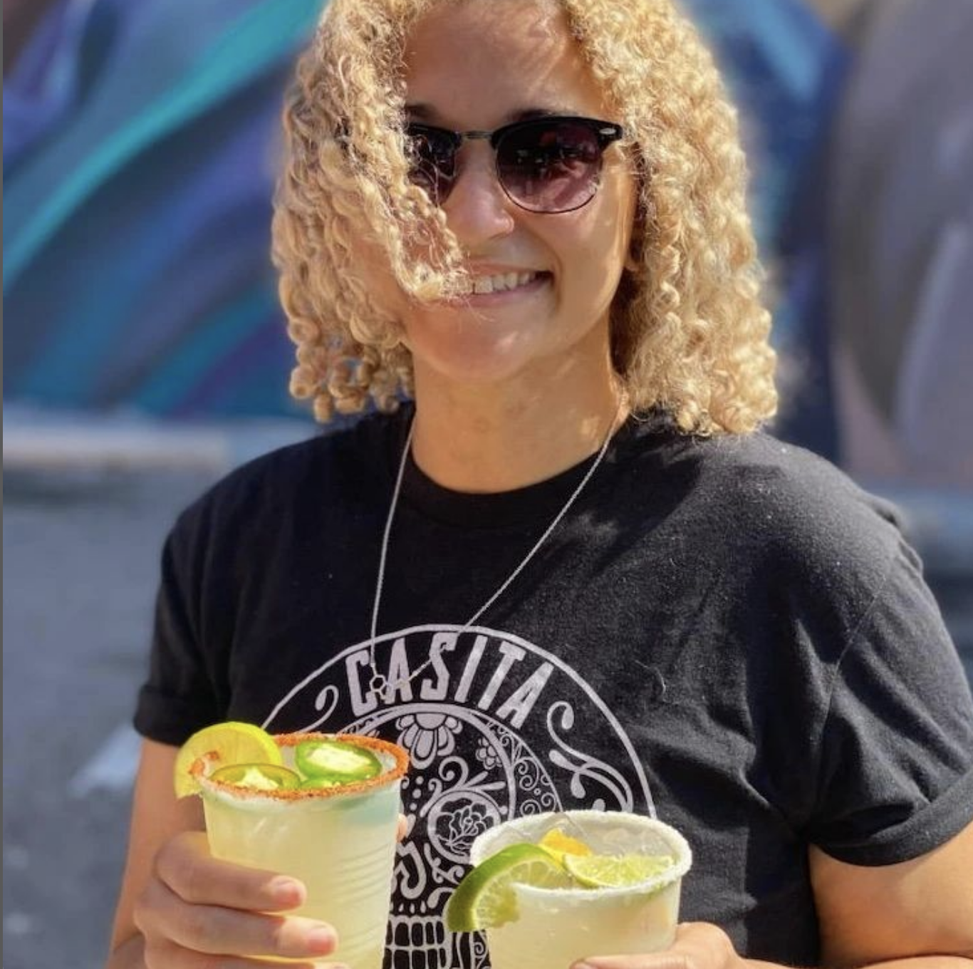 A woman holds two margaritas